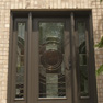 exterior view of a brown single entrance door with sidelites and tall shaped transom featuring full length decorative glass