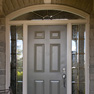 exterior view of a single steel grey entrance door with sidelites and shaped transom featuring decorative glass
