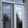 exterior deck view of grey stained vinyl terrace door and white vinyl fixed door wth transoms