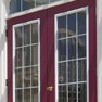 exterior deck view of red stained vinyl two panel terrace door and transom featuring grills