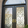 exterior view of a black double entrance door and half round transom featuring full wrought iron and glass inserts in the doors