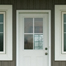 exterior view of a single white entrance door with four glass panels located in the upper half of the door