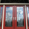 exterior view of red double entrance doors and sidelites featuring full length decorative glass and half round transom