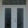 exterior view of white double doors with full length decorative glass and full width rectangular transom also featuring decorative glass