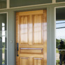 exterior view of a wood single entrance door with sidelites and transon surrounded by green decorative wood