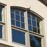 exterior view of four panel shaped top wicker stained vinyl slider windows with matching side windows featuring grills