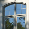 exterior view of dover grey stained vinyl casement windows with shaped top, grills and flower box