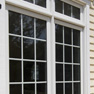 exterior patio view of white vinyl fixed windows with transom featuring grills