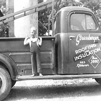 Young Strassburger boy standing on the running board of the family business truck