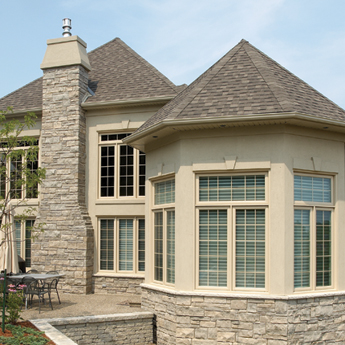 View from the backyard of a house with canyon clay coloured vinyl windows with grilles