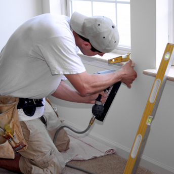 Carpenter installs the final trim around a newly installed window