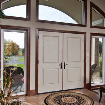 View from inside the foyer of a home of beige double entrance doors with large fixed sash sidelites and curved three panel transom